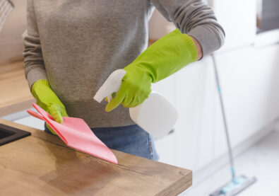 Close up woman cleaning kitchen using cleanser spray and cloth.